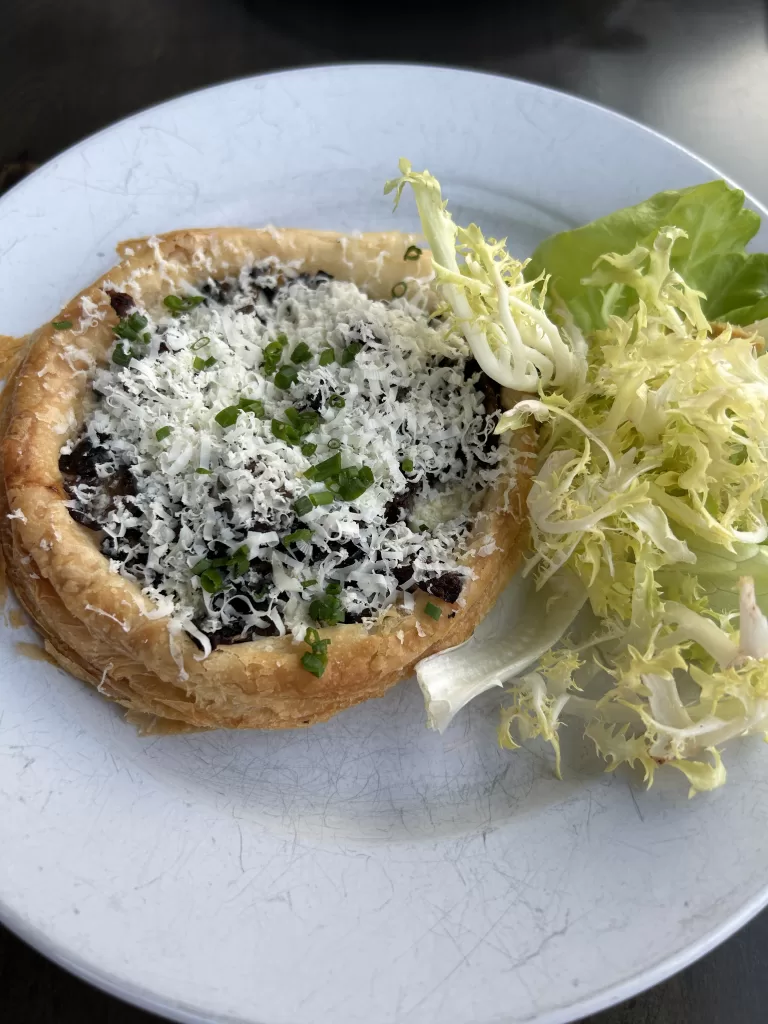 Appetizer on a plate with salad greens on the side.