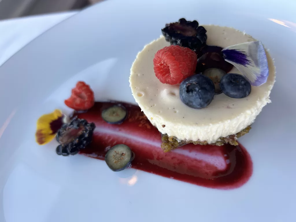 Mini cheesecake with berries and flower garnish on a plate