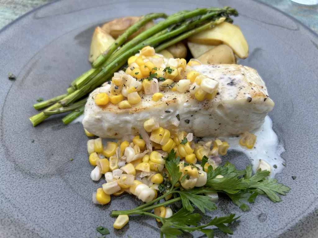 Fish meal with corn garnish and vegetables on a plate