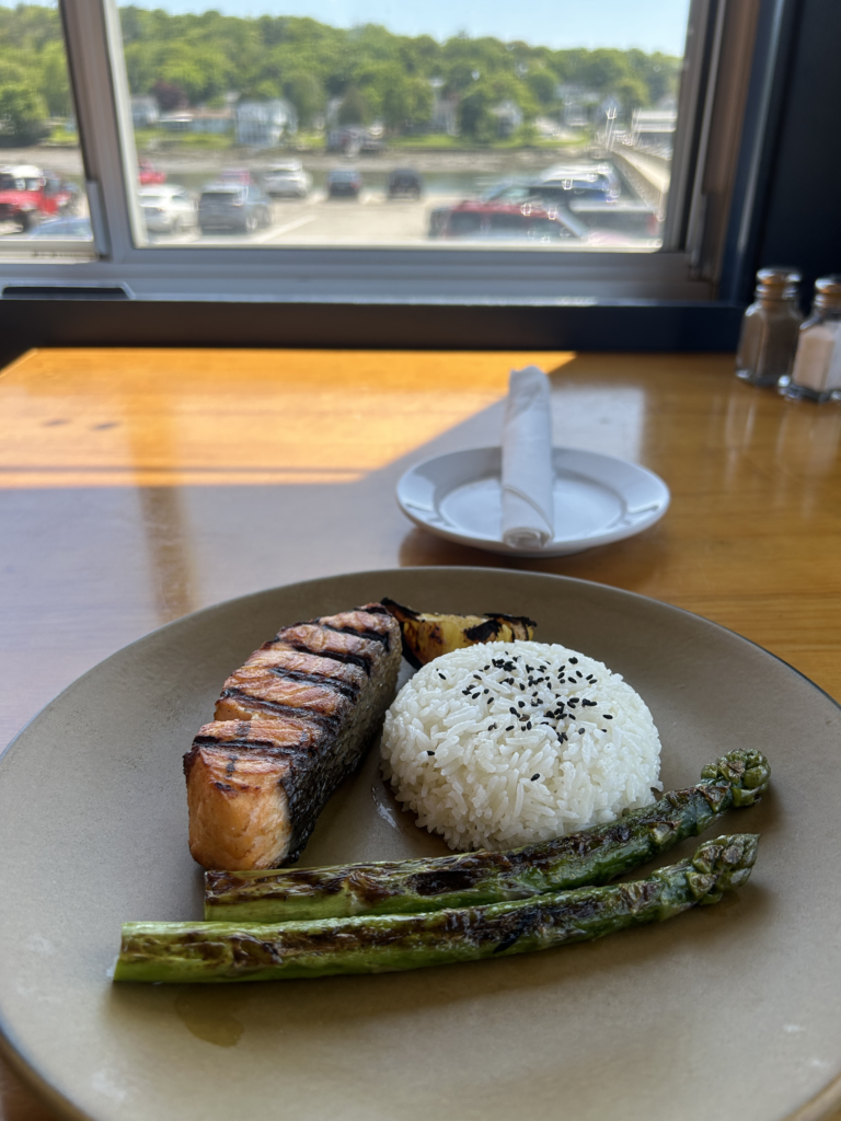 Image of a grilled salmon with rice and asparagus with views of the harbor