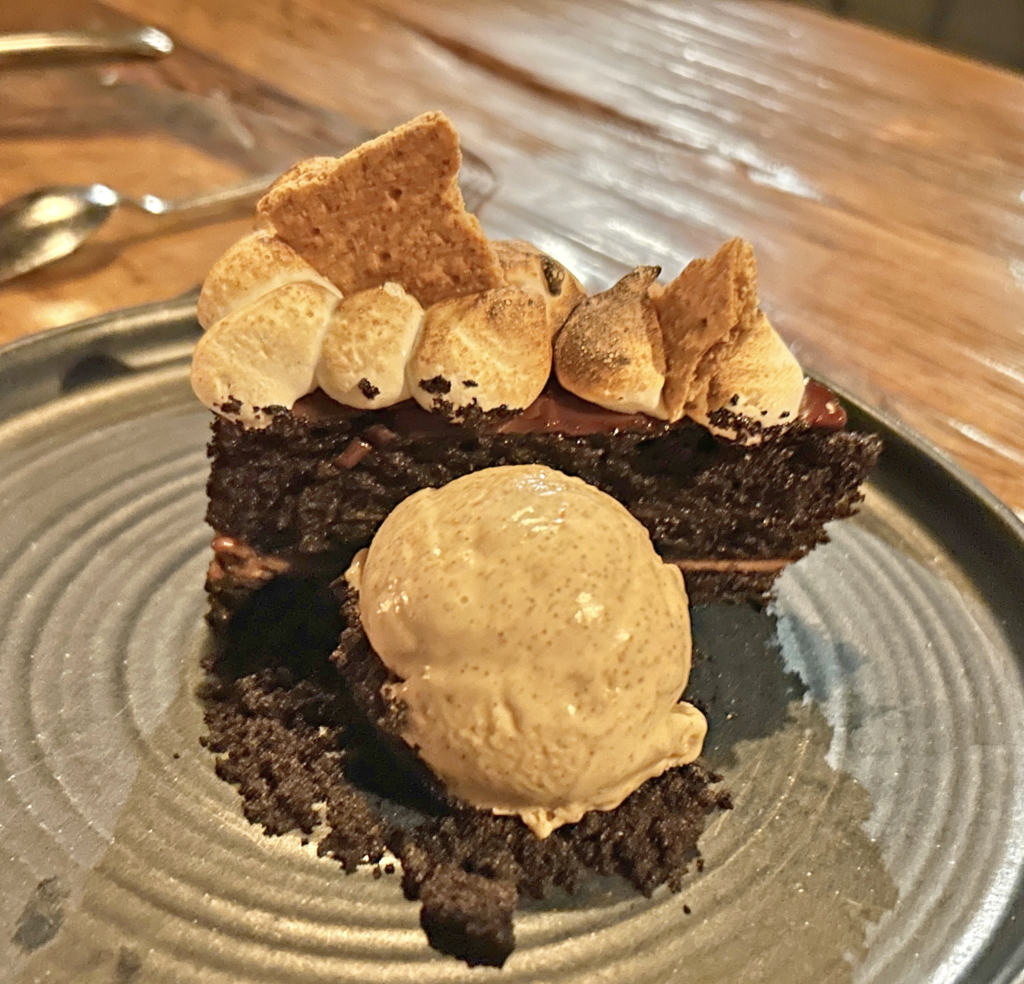 Image of a s'mores cake with a scoop of ice cream on the plate