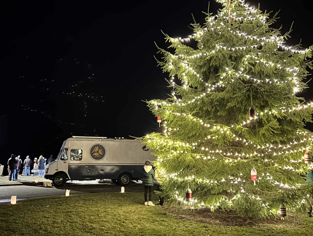 Christmas tree decorated in lights with a food truck in the background