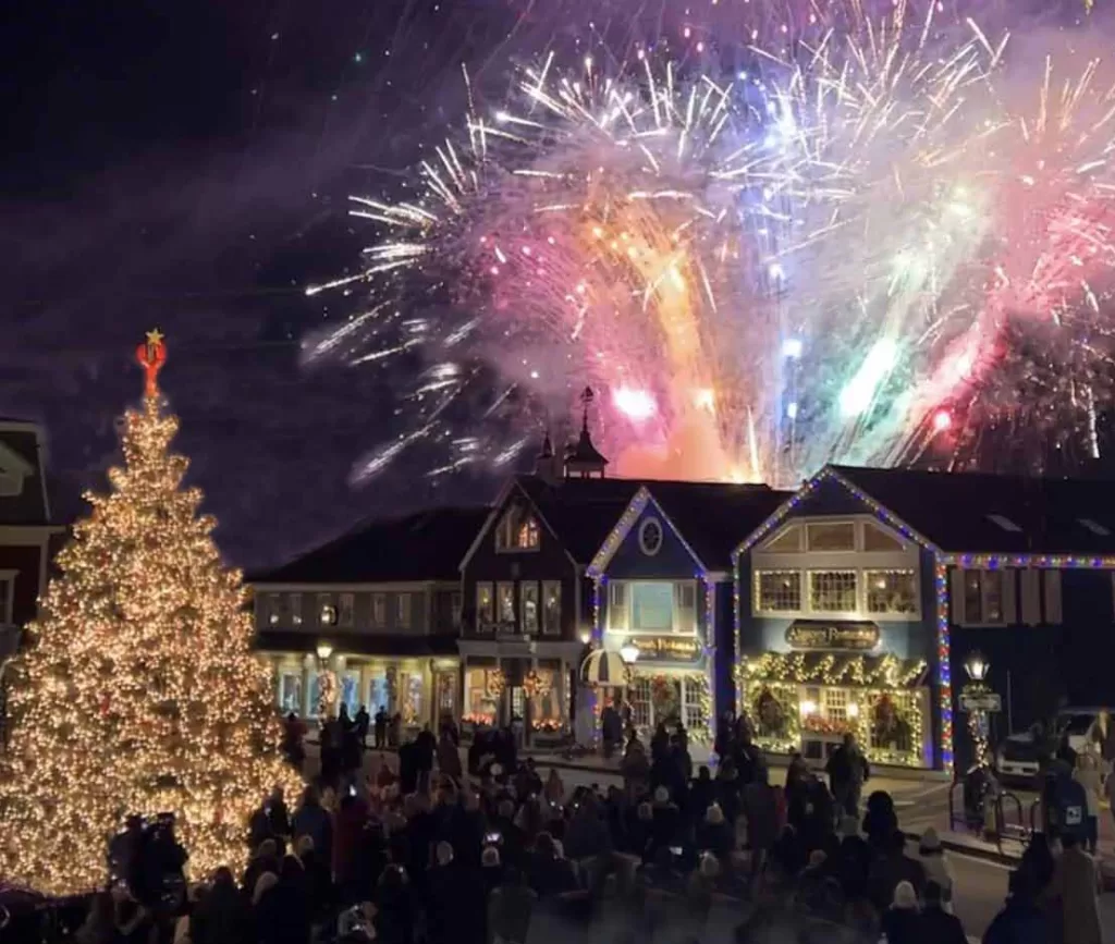 Christmas tree and store fronts lit with Christmas lights, and fireworks in the sky